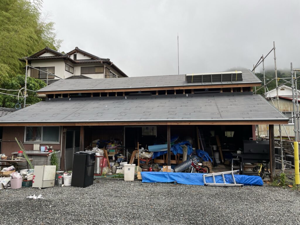 納屋の屋根に防水シートを施工し、雨仕舞いを強化した様子