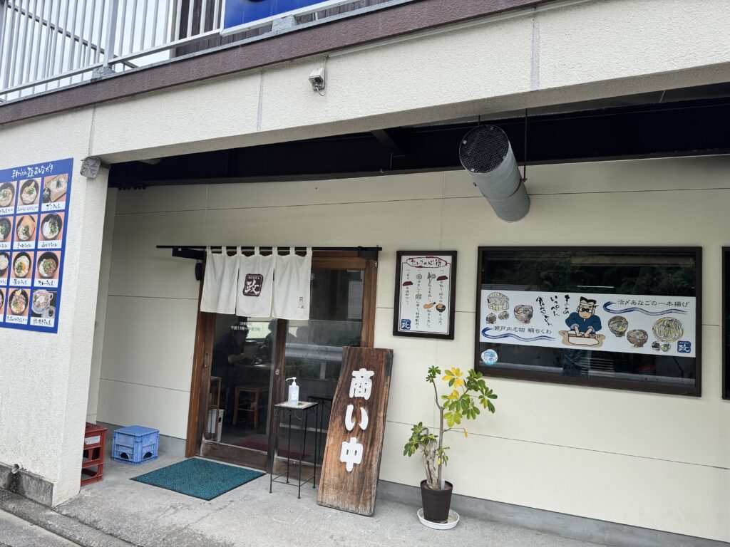 手打ちうどん「政」の店舗入口。のれんと木製の看板がある外観。