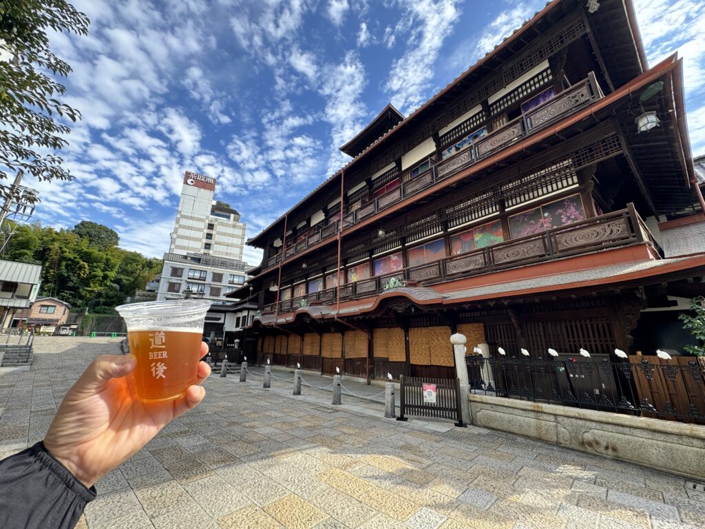 道後温泉本館を背景に道後ビールで湯上がり乾杯。青空に映える温泉街の一枚。