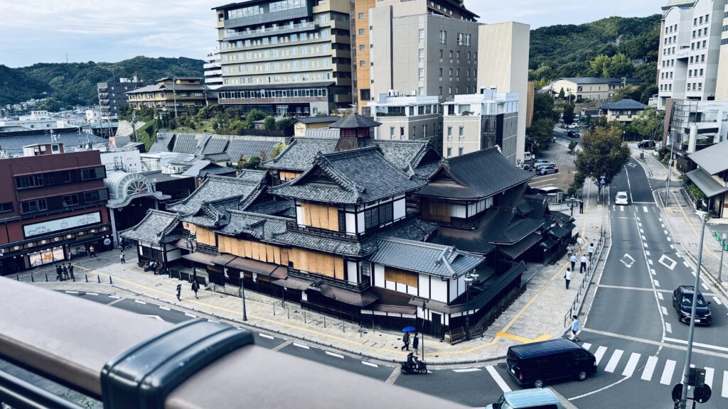 空の散歩道から見下ろす道後温泉本館の俯瞰。屋根の造形美が際立つ絶景スポット。