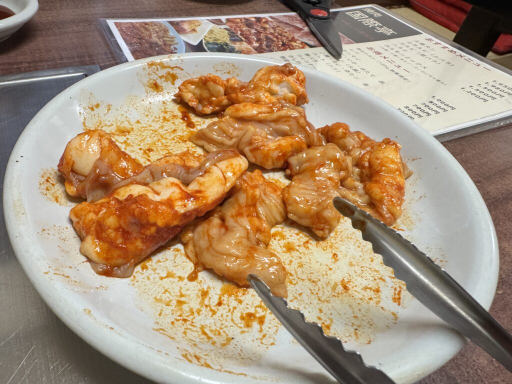 焼肉店のホルモン盛り。赤いタレが絡む生ホルモンのアップ。