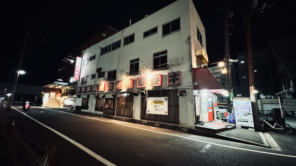 夜の焼肉「国際亭」外観を広角で撮影。街灯と看板が映える。